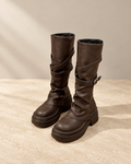 Brown thick-heel knee-high riding boots with wrap straps, studio view