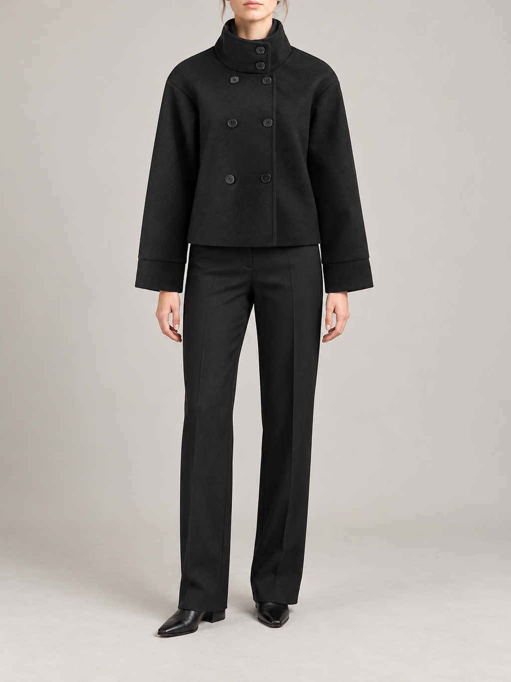 black short boxy high-neck coat with asymmetric button front and broad straight sleeves, front view on a model