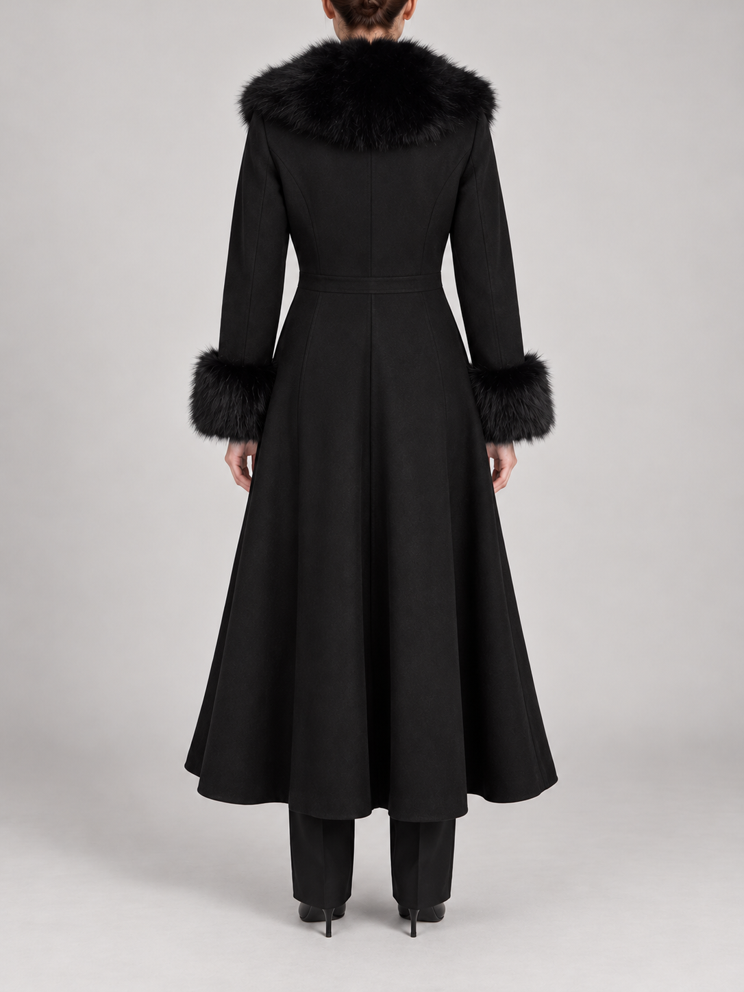 black calf-length flared coat with fitted waist, voluminous faux-fur shawl collar and furry cuffs, back view on a model