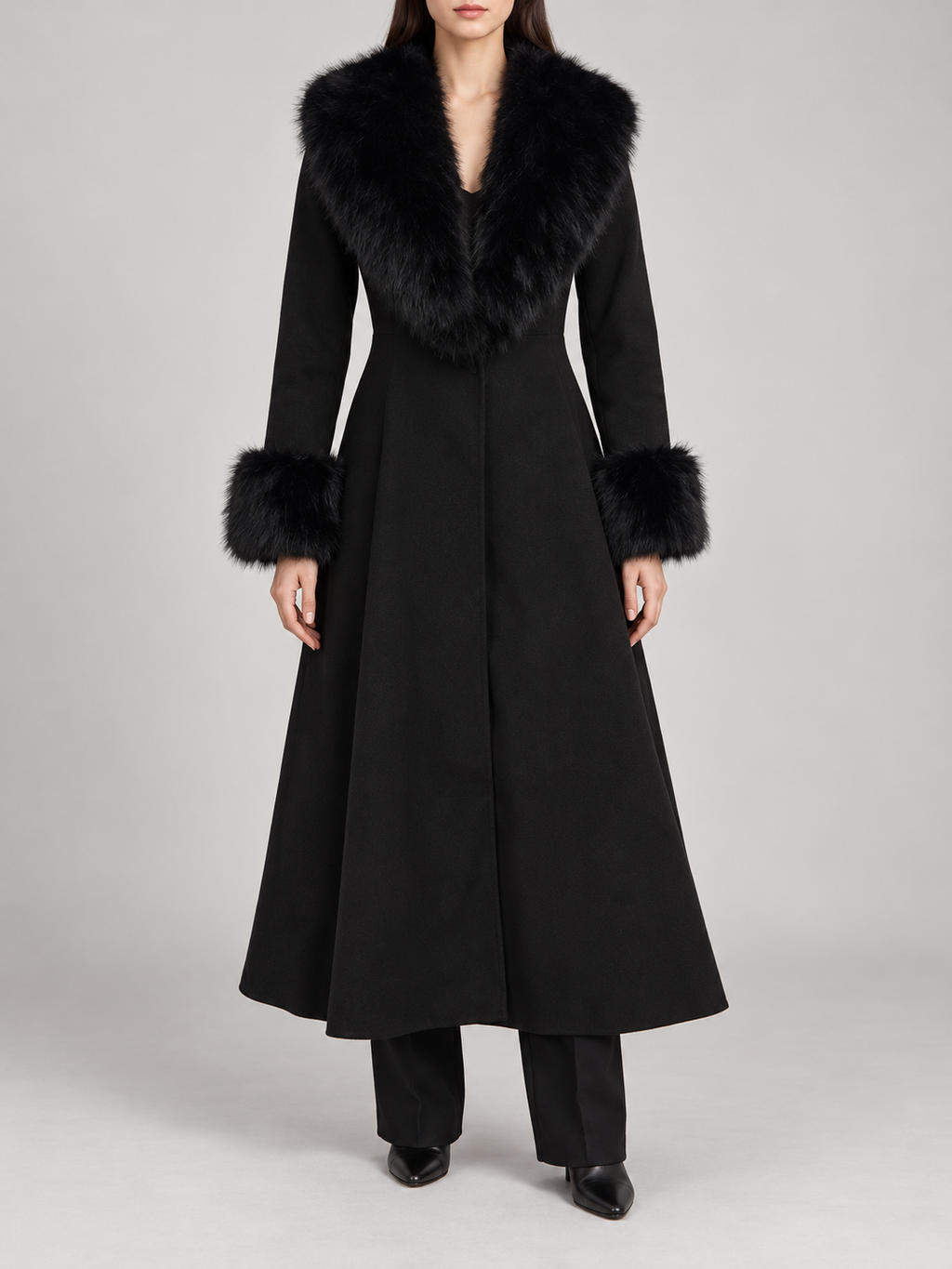 black calf-length flared coat with fitted waist, voluminous faux-fur shawl collar and furry cuffs, front view on a model