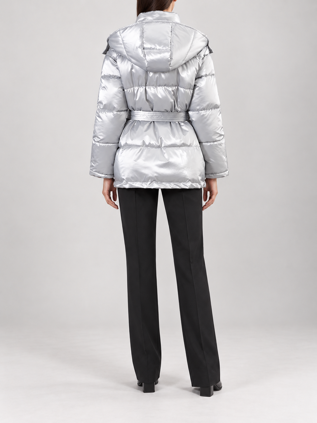 silver glossy quilted hooded puffer jacket with self-tie waist belt and horizontal panels, back view on a model