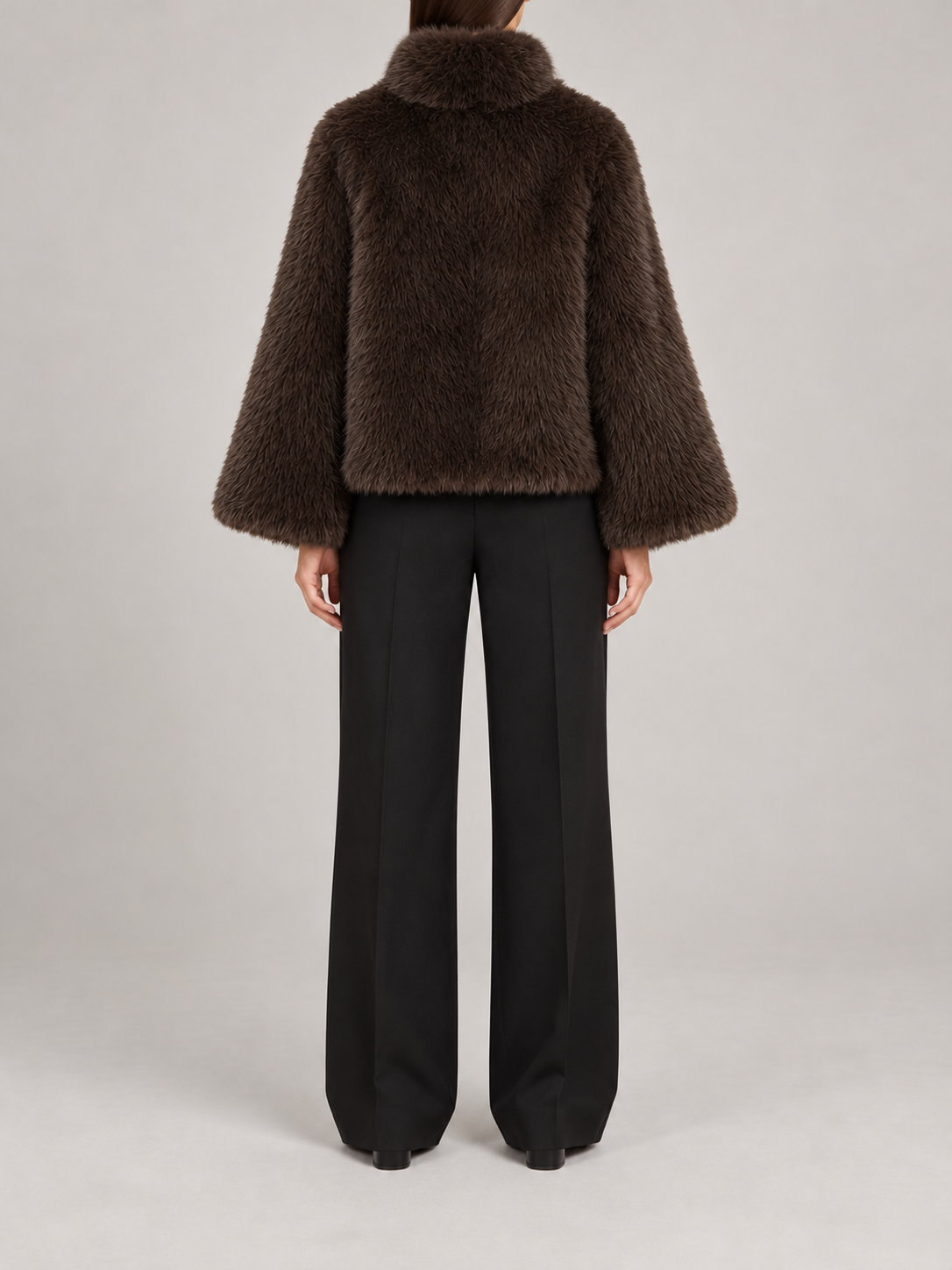 dark brown short plush faux-fur jacket with rounded high collar and wide straight sleeves, back view on a model