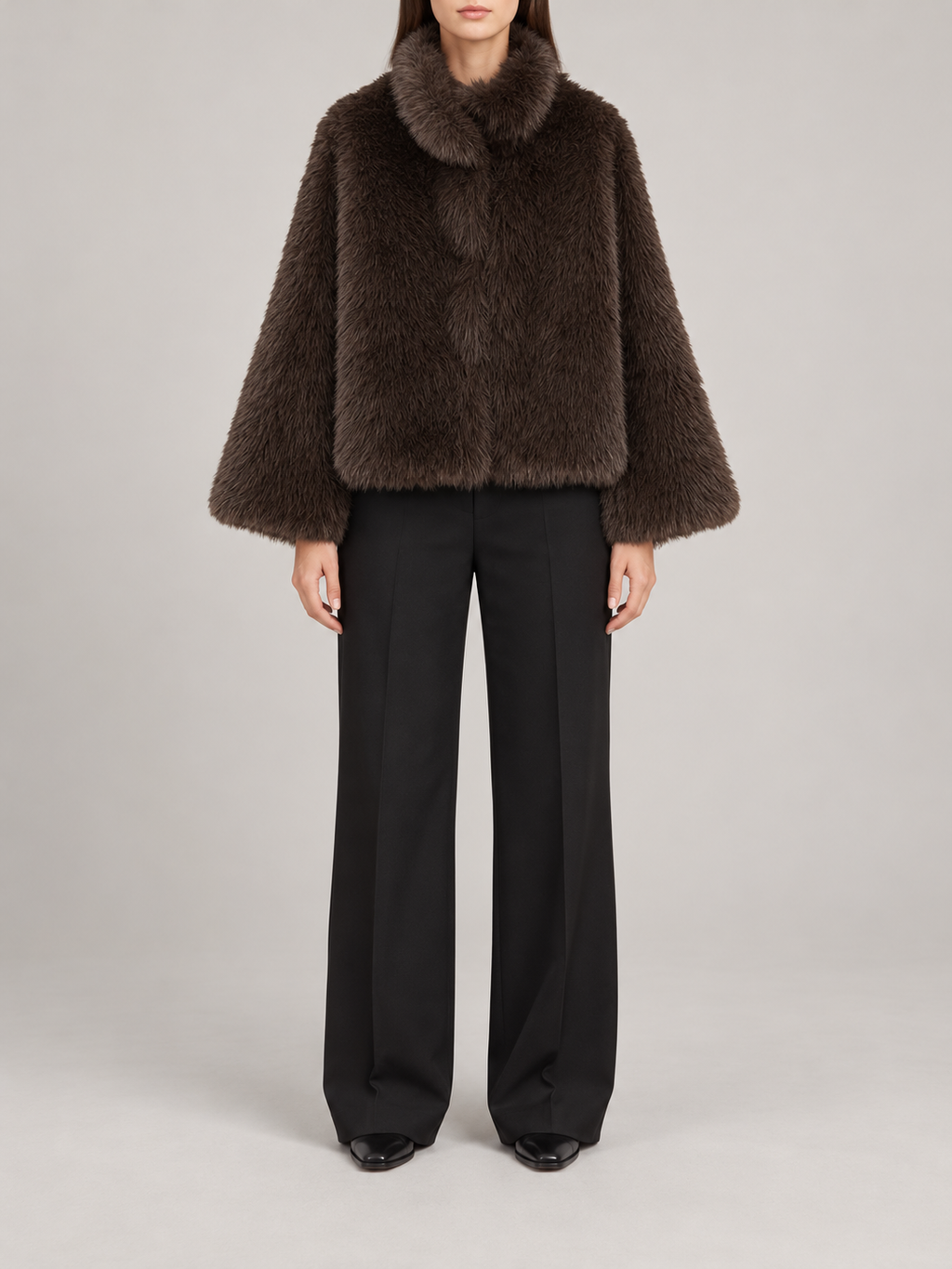 dark brown short plush faux-fur jacket with rounded high collar and wide straight sleeves, front view on a model