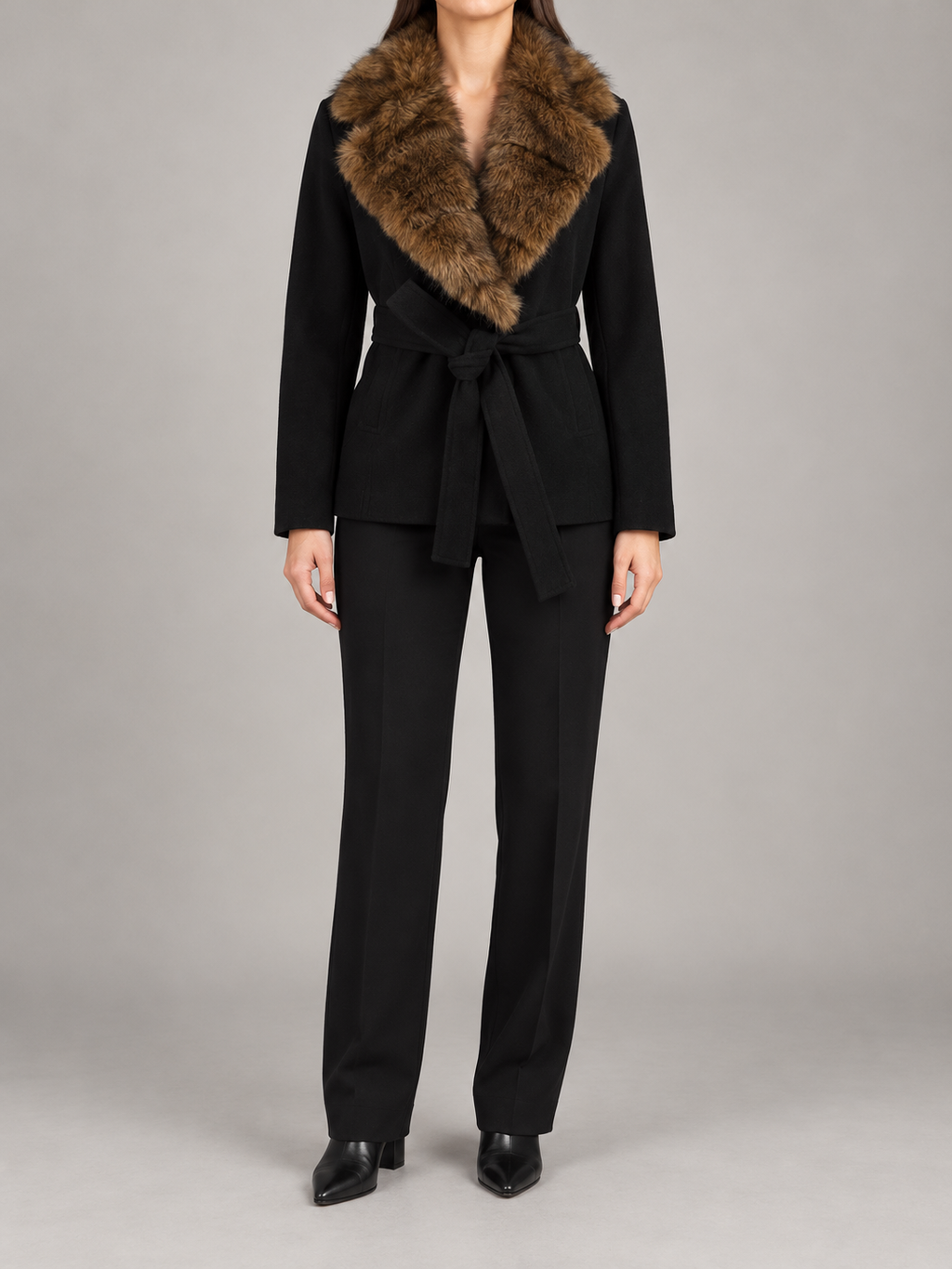 black hip-length wrap coat with brown faux-fur shawl collar and fabric waist tie, front view on a model